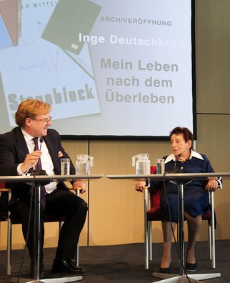 André Schmitz und Inge Deutschkron sitzen vor einem Plakat